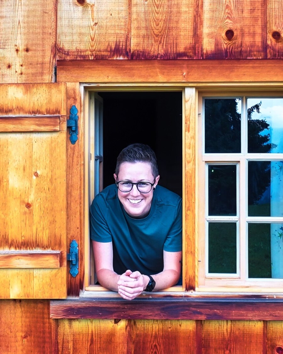Karo von The Timbertones lehnt lachend aus dem Fenster einer Holzhütte